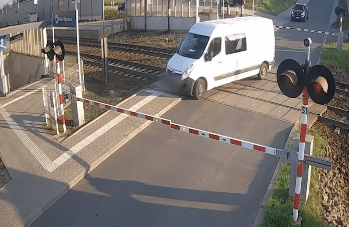 White van crossing railroad tracks.