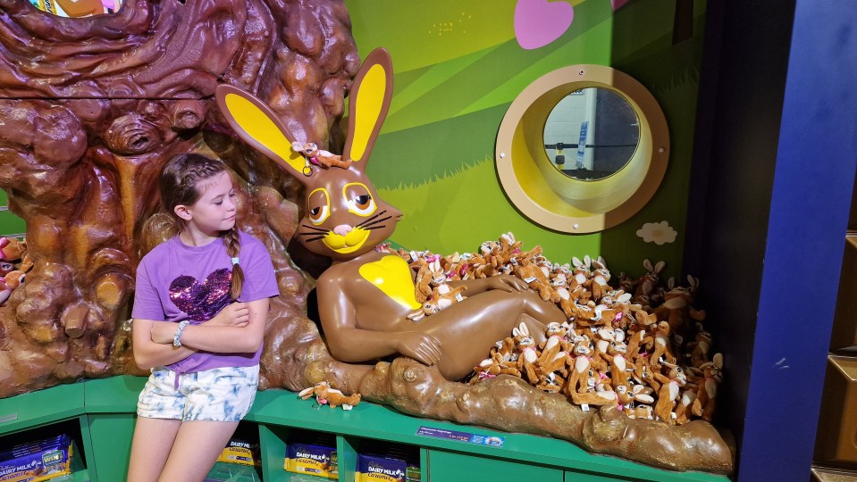Girl at Cadbury World next to a large chocolate bunny surrounded by smaller plush bunnies.