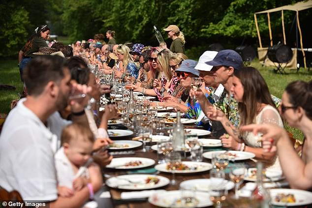 Pictured: guests enjoy Ben Quinn's sumptuous so-called ‘long-table banquet' in the woods during Wilderness Festival at Cornbury Park on August 1
