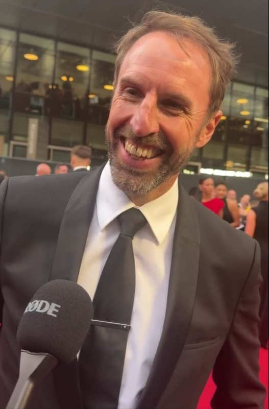Man in suit being interviewed on a red carpet.