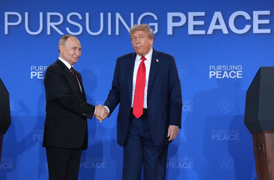 Donald Trump and Vladimir Putin shaking hands at a press conference.