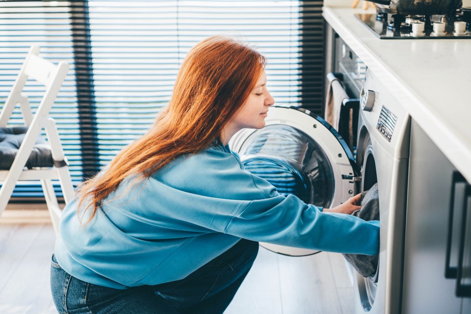 Woman loading laundry into washing machine.