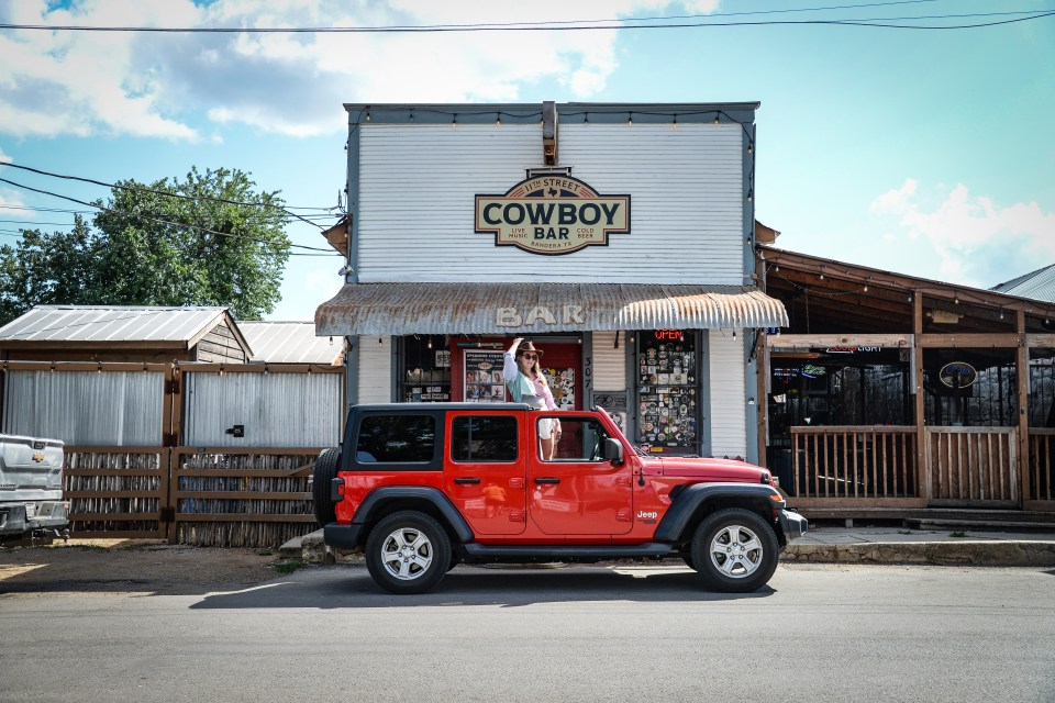 Red Jeep parked in front of the Cowboy Bar in Bandera, Texas.