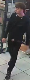 Surveillance image of a man in a black shirt and pants.
