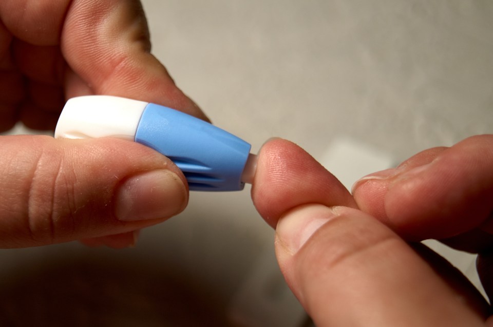 Close-up of a person using a lancet on their finger for an HIV test.