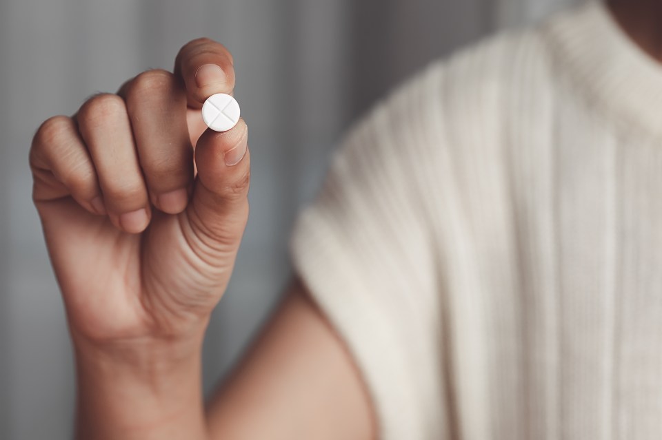 Hand holding a white pill.