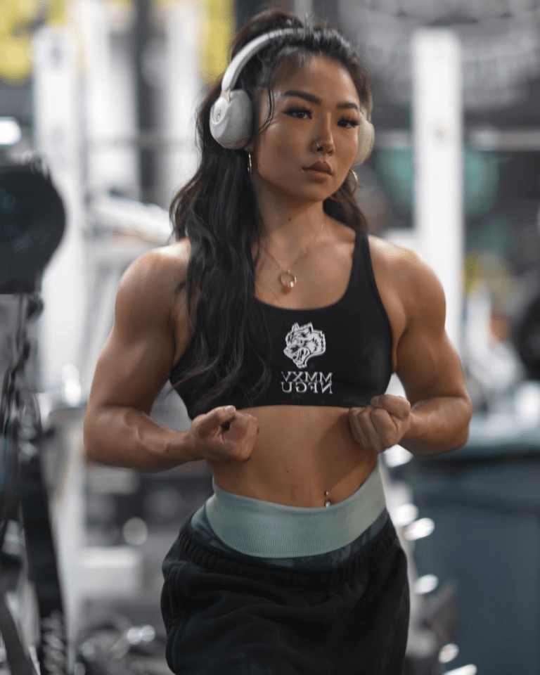 Muscular woman wearing headphones in a gym.