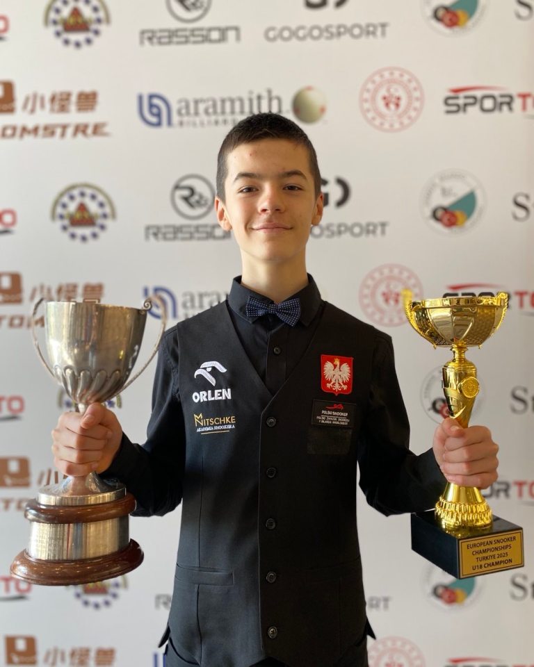 Young snooker player holding two trophies.