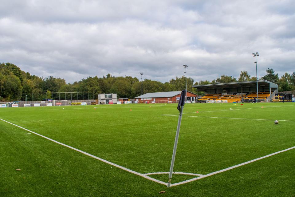 Soccer field with stands and trees in the background.