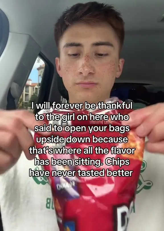 Person holding a bag of chips upside down, explaining that's how to get the best flavor.
