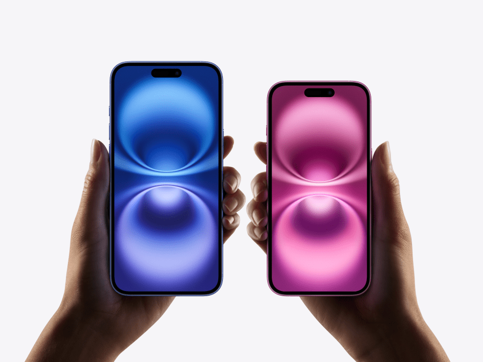 Two hands holding iPhone 16 models in purple and pink.