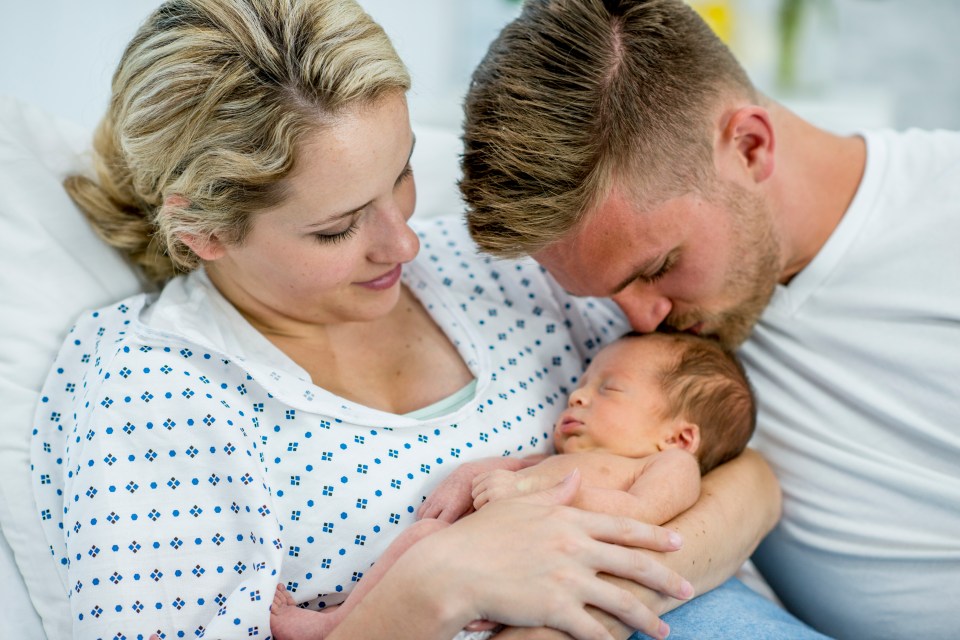 Mother and father holding their newborn baby in a hospital room.