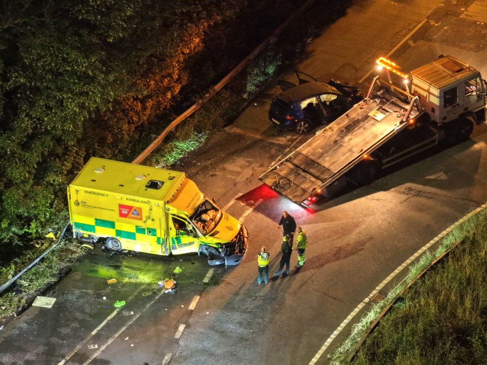 Nighttime photo of a car accident involving an ambulance and a car.  Emergency personnel are at the scene.