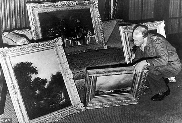 A war-era photo showing a German officer examining paintings of the Goudstikker collection