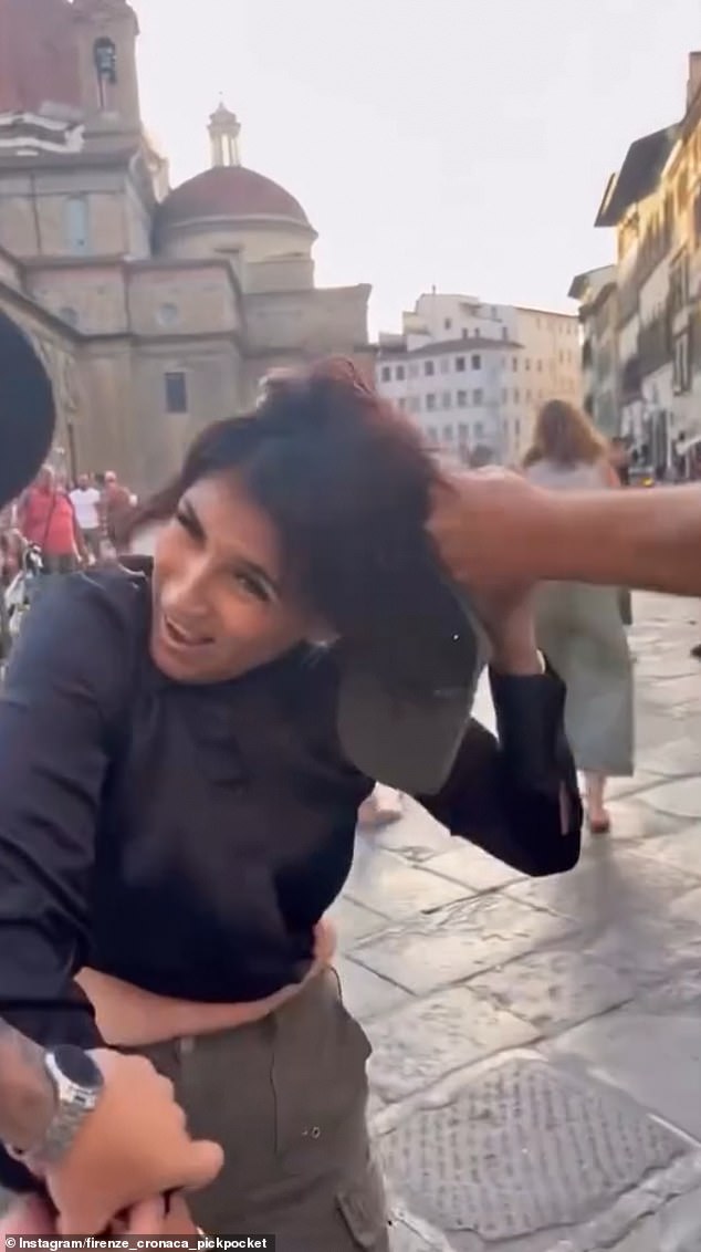 The woman, who claims to be pregnant after being caught, is held by the hair and arms and stopped from stealing the bag at Piazza di San Lorenzo, a square in Florence