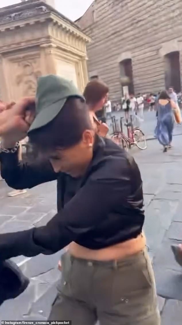 The victim's husband and another man keep hold of the thief as she tries to wriggle away