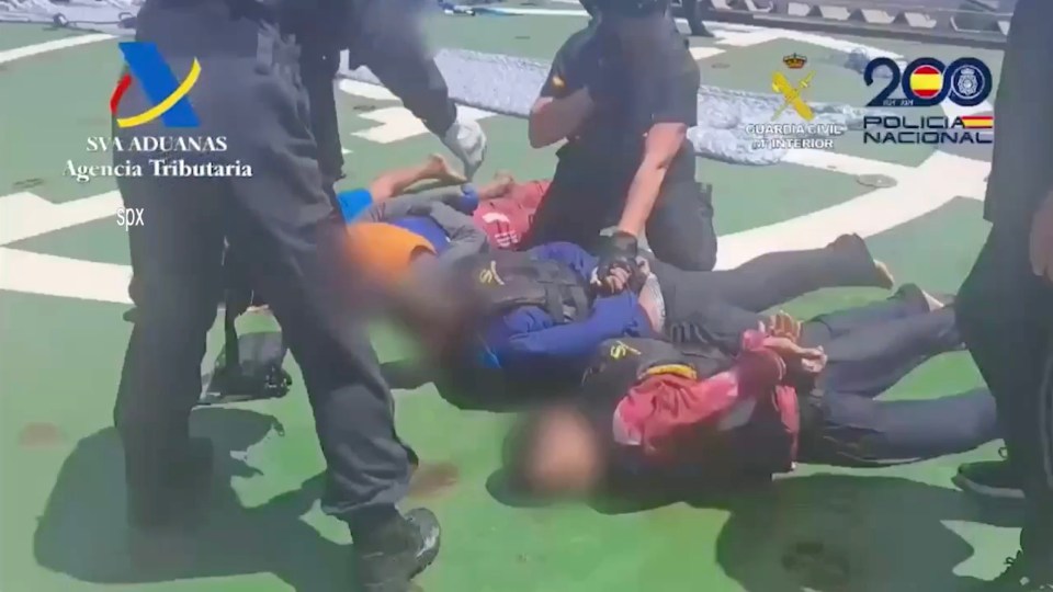Arrested suspects lying on a ship deck.