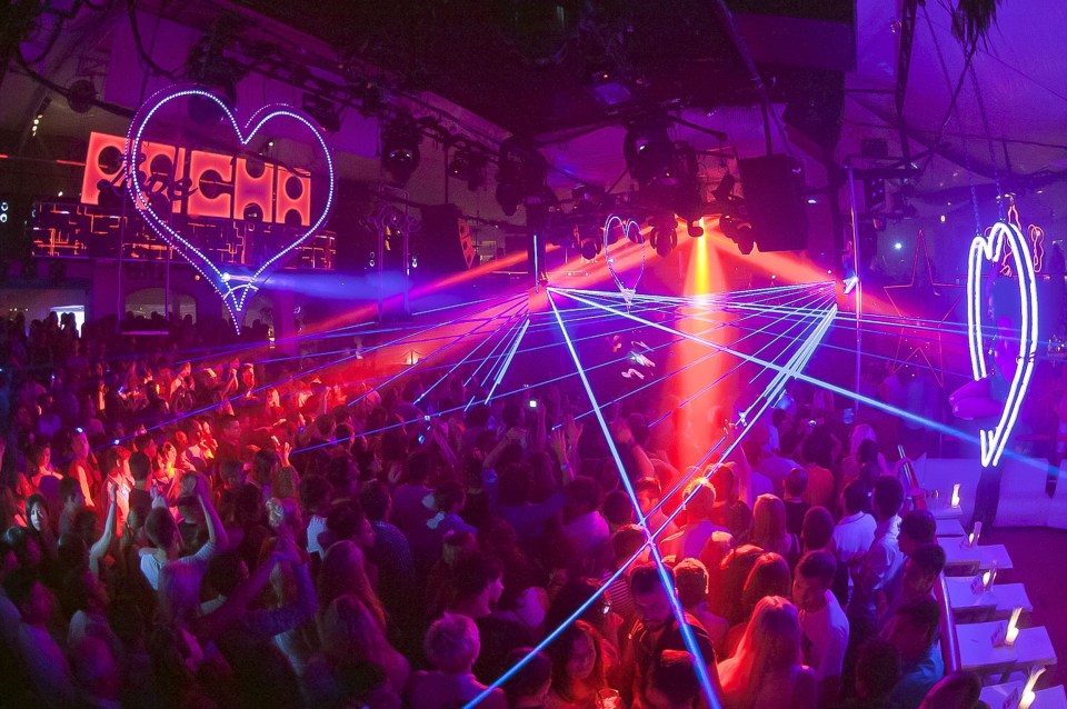 Crowded nightclub dance floor with laser lights.