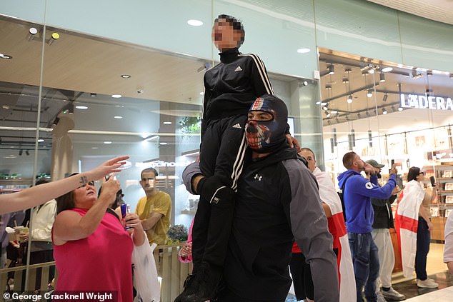 A child is carried away after being caught in pepper spray as anti migrant protestors clashed with police in Canary Wharf