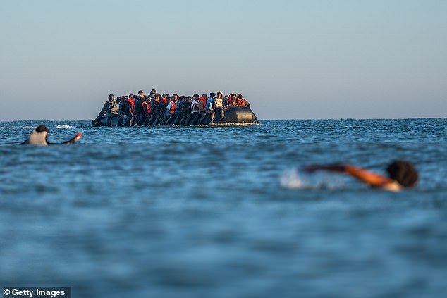 People swim to try and board a dinghy in the English Channel in Gravelines, northern France