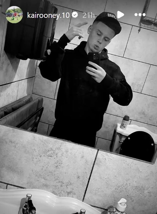 Black and white photo of Kai Rooney taking a selfie in a bathroom.