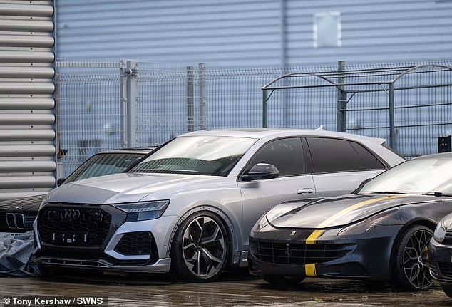 Expensive cars such as Audis and Ferraris are sat in the parking lot of the dealership