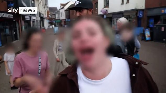 The woman moves in front of the camera while shouting a string of obscenities directed towards Zahin