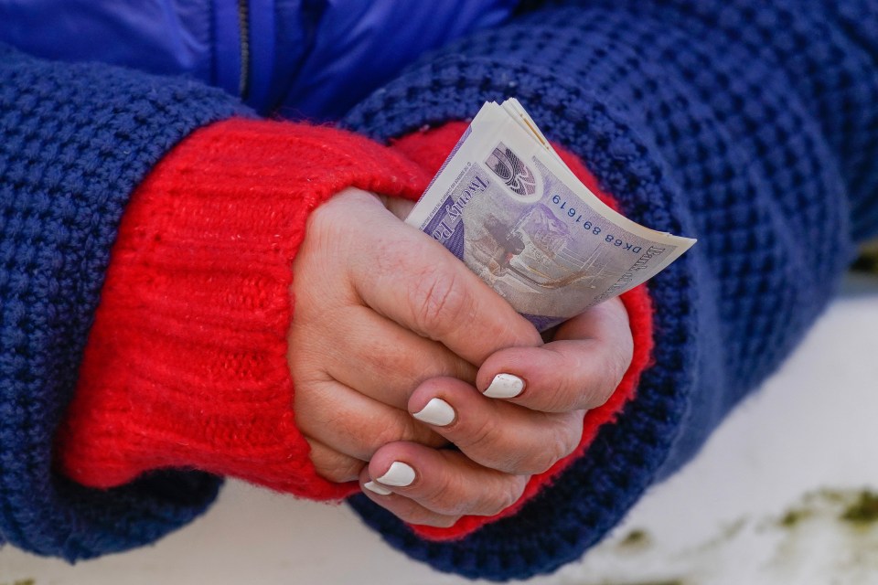 Hands holding British banknotes.