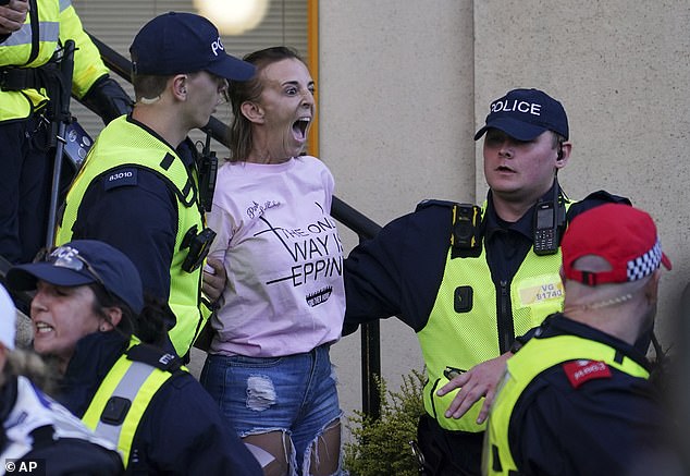 She was then seized by police and taken away in a van - as fellow demonstrators standing nearby reacted with fury