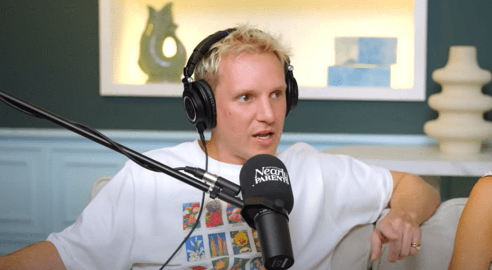 Man wearing headphones speaks into a microphone on a podcast.