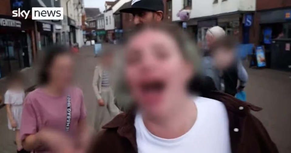 TV CHAOS Vile moment woman storms TV interview with beer in hand to hurl racist abuse at local businessman - with KIDS in tow, , This is the moment a local business owner is racially abused in broad daylight by foul-mouthed passerby in Nuneaton town centre. , , In a video circulating on social media, local business owner Zahin, 32, was being interviewed by Sky News about the divide in the town over attitides to asylum seekers., , He has only just started to speak, stating his age, when he is interrupted by two women walking along the street with what appears to be a group of children.