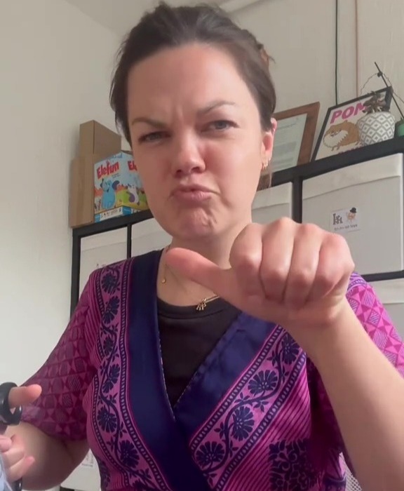 Woman giving thumbs down, saying "How was your day?"
