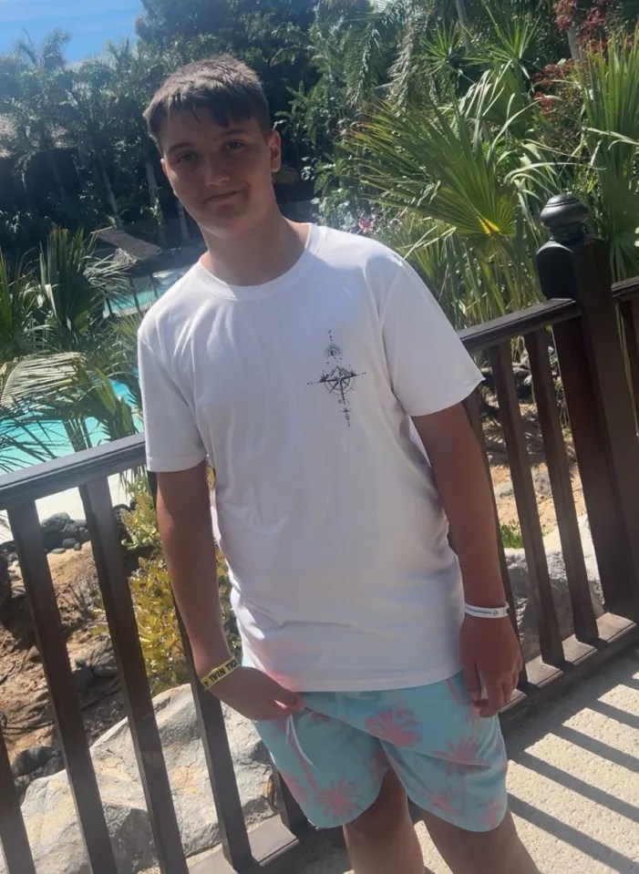 Teenager in white shirt and swim trunks near a pool.