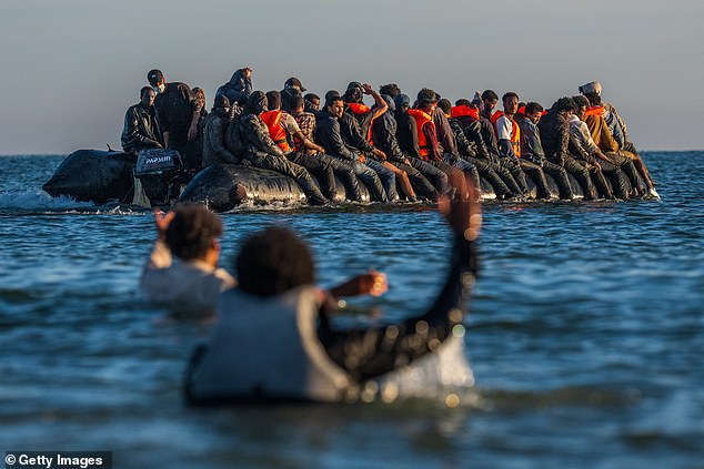 Migrants in lifejackets wave to a dinghy leaving Gravelines in northern France last month