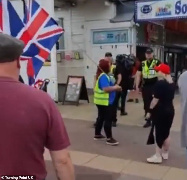 The pair sought assistance from nearby police officers as the man filming them shouted: 'Go on! F*** off'