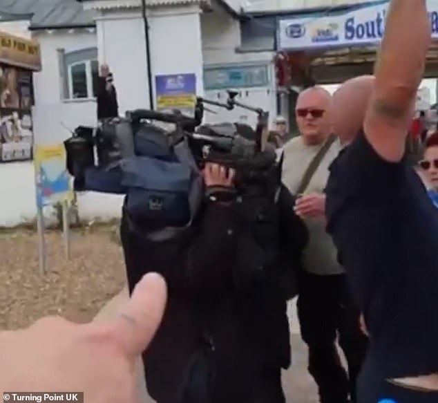Ms Cridland, a BBC South journalist, put up her hood and the pair then walked away as protesters shouted: 'BBC not welcome here'