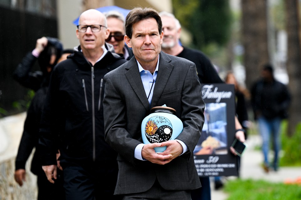 A man carries a decorated urn while walking with others.