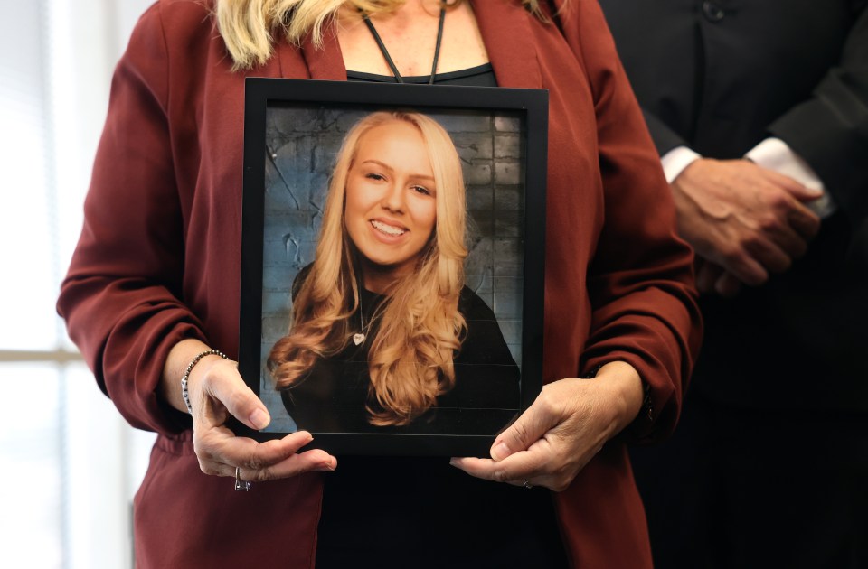 Woman holding framed photo of her daughter.