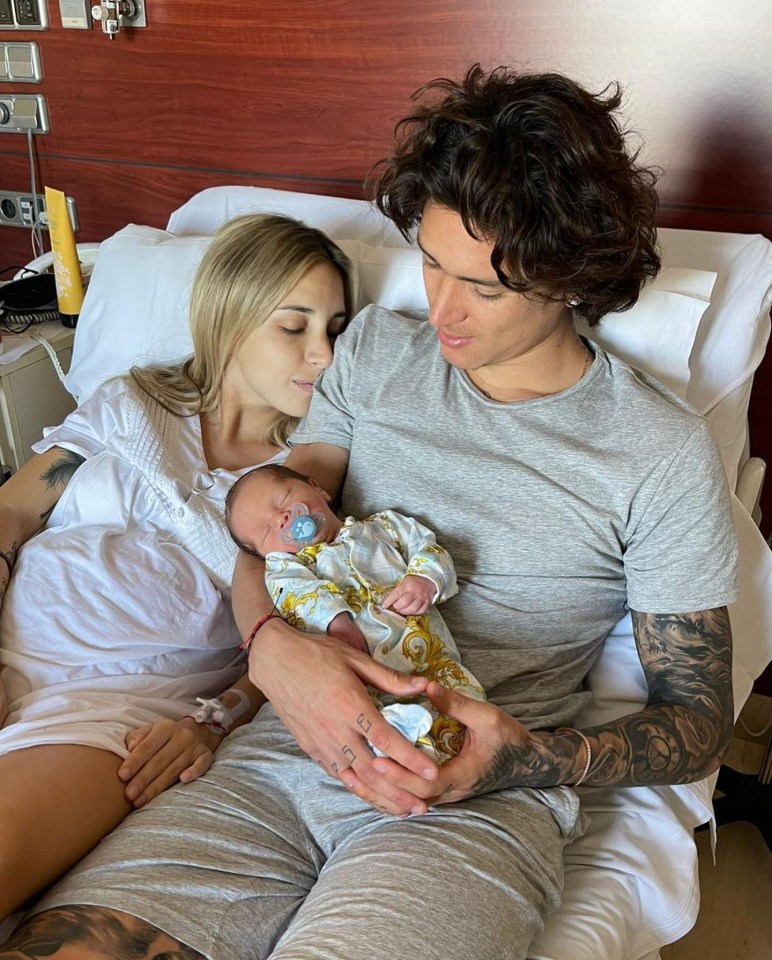 Parents holding their newborn baby in a hospital bed.