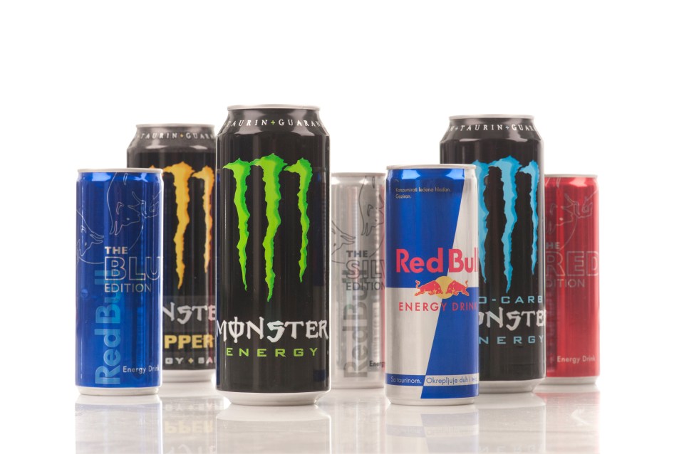 Several cans of Red Bull and Monster energy drinks.
