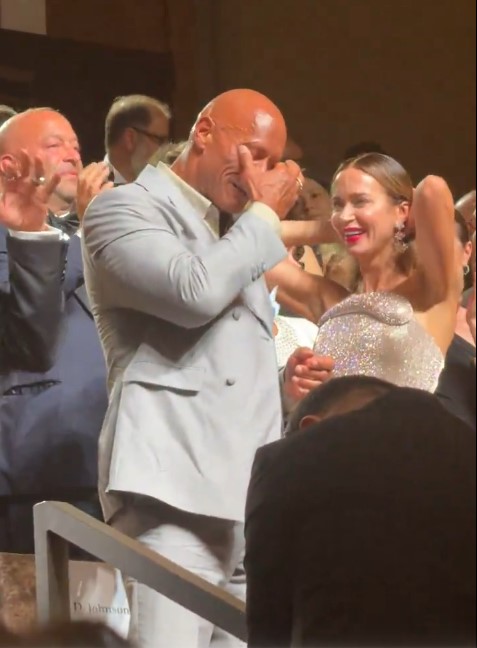 The Rock crying while embracing a woman.