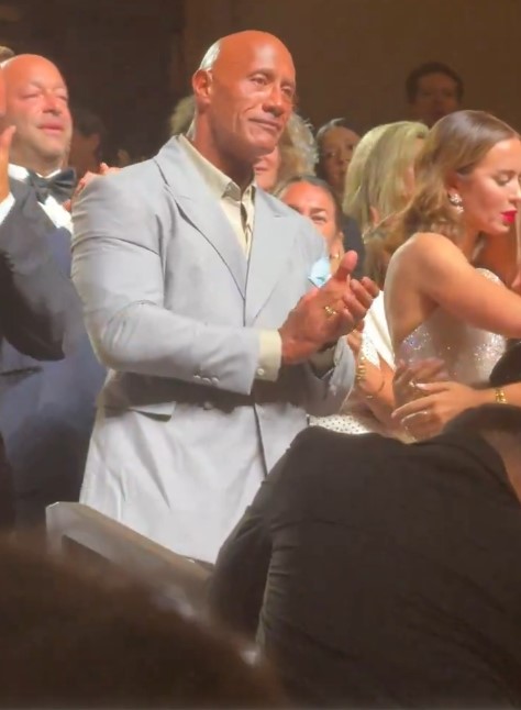 The Rock applauding at a movie premiere.
