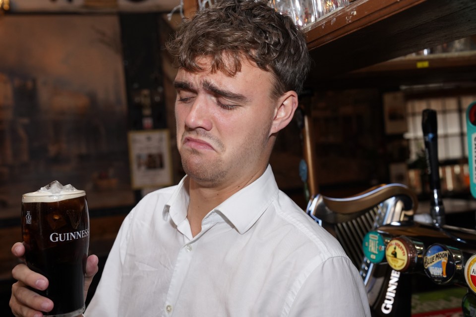 Man grimacing while holding a Guinness with ice.
