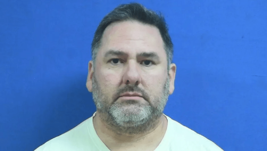 Mugshot of a man with graying hair and a beard.