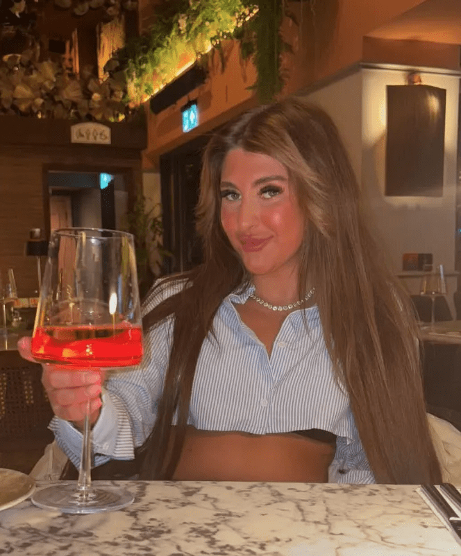 Woman holding a glass of Aperol Spritz in a restaurant.
