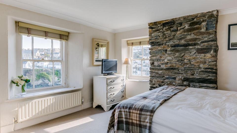 Bedroom with sea view and stone wall.
