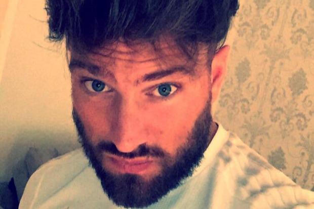 Close-up selfie of a man with blue eyes and a beard.