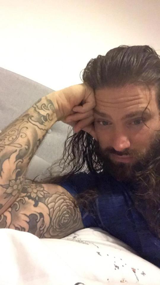 Portrait of a man with long hair and tattoos.