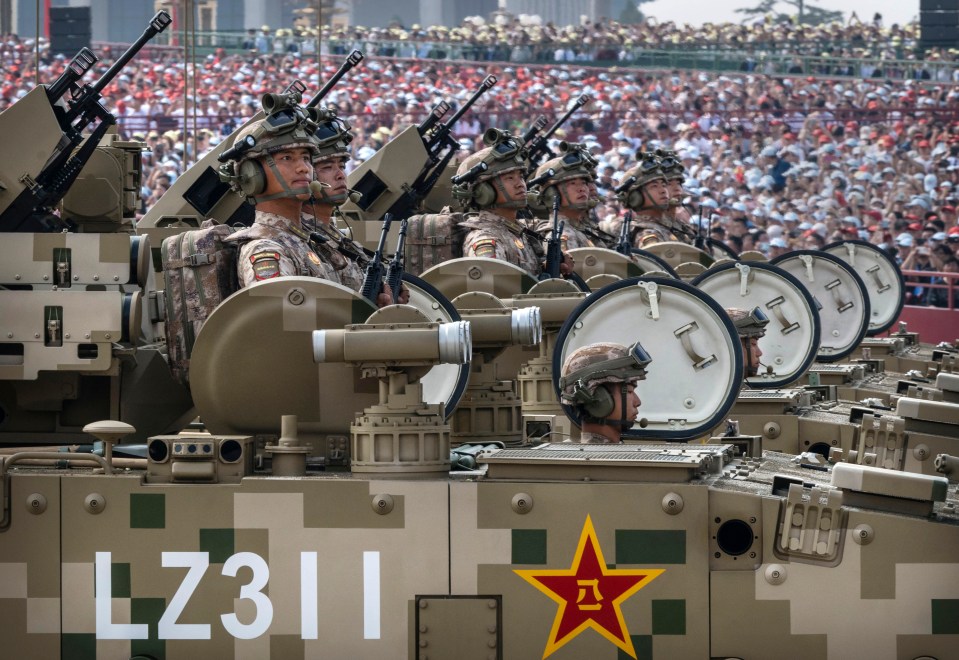 Chinese soldiers in armored vehicles during a military parade.