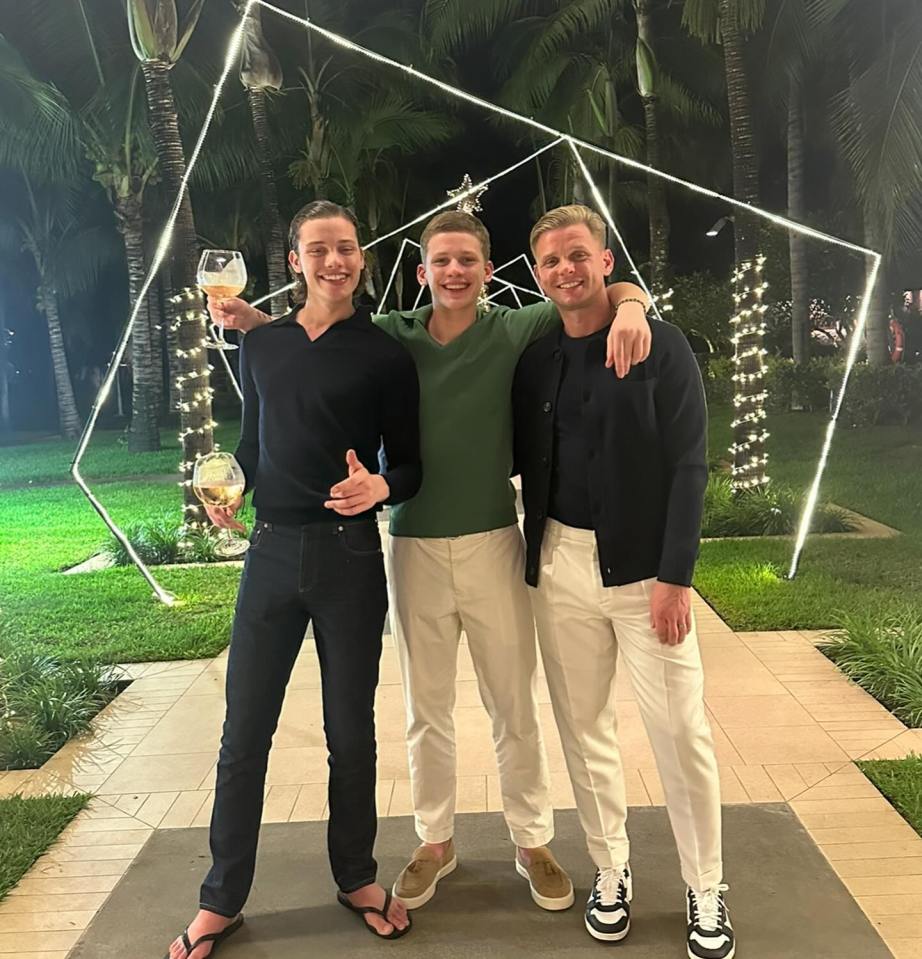 Three men posing together, holding wine glasses.